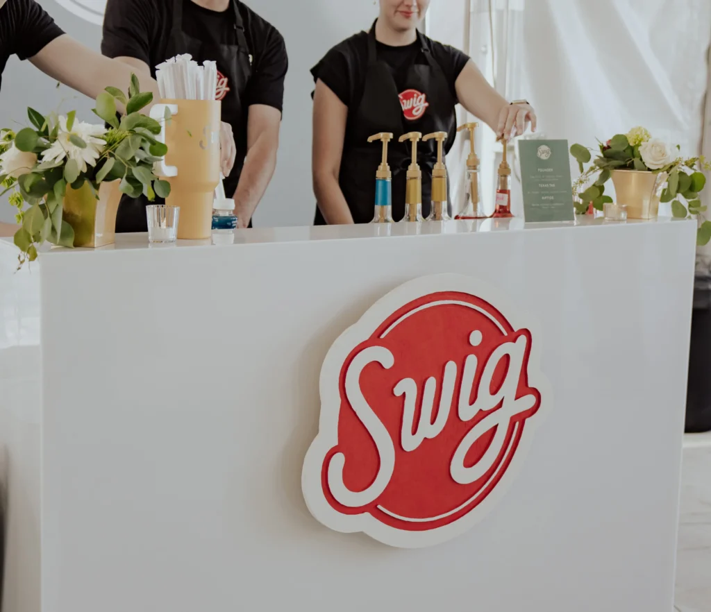 Swig catering setup with branded soda bar, syrups, and staff serving custom dirty sodas at an event.
